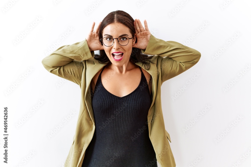 Young brunette woman standing over isolated background trying to hear both hands on ear gesture, curious for gossip. hearing problem, deaf Young brunette woman standing over isolated background trying to hear both hands on ear gesture, curious for gossip. hearing problem, deaf