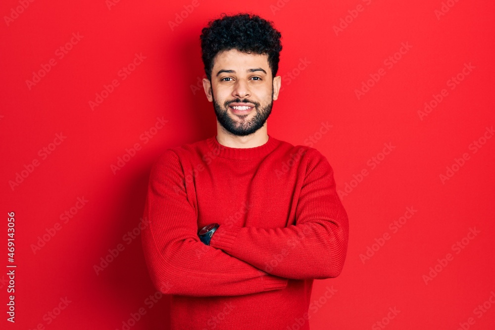 Young arab man with beard wearing casual red sweater happy face smiling with crossed arms looking at the camera. positive person.