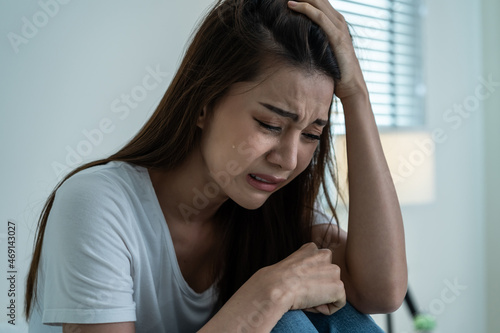 Asian beautiful depression girl crying in tears sit on bed in bedroom. 
