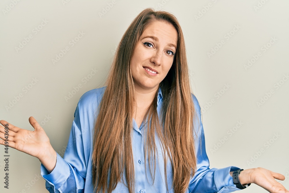 Young blonde woman wearing casual blue shirt clueless and confused expression with arms and hands raised. doubt concept. Young blonde woman wearing casual blue shirt clueless and confused expression with arms and hands raised. doubt concept.