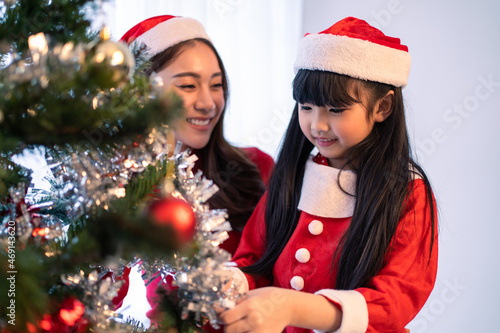 Asian lovely family, mother and kid daughter decorating Christmas tree. 