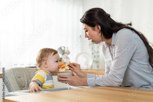Caucasian beautiful mother take care of baby boy toddler in kitchen. 