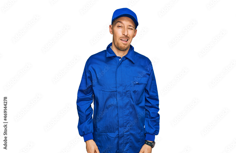 Bald man with beard wearing builder jumpsuit uniform winking looking at the camera with sexy expression, cheerful and happy face. Bald man with beard wearing builder jumpsuit uniform winking looking at the camera with sexy expression, cheerful and happy face.