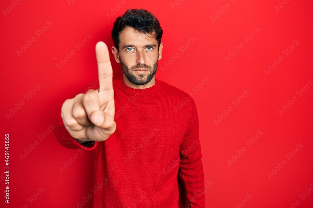 Handsome man with beard wearing casual red sweater pointing with finger up and angry expression, showing no gesture Handsome man with beard wearing casual red sweater pointing with finger up and angry expression, showing no gesture