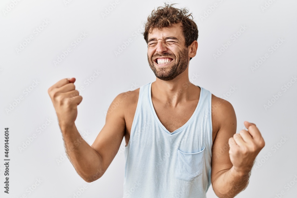 Young handsome man standing over isolated background very happy and excited doing winner gesture with arms raised, smiling and screaming for success. celebration concept. Young handsome man standing over isolated background very happy and excited doing winner gesture with arms raised, smiling and screaming for success. celebration concept.