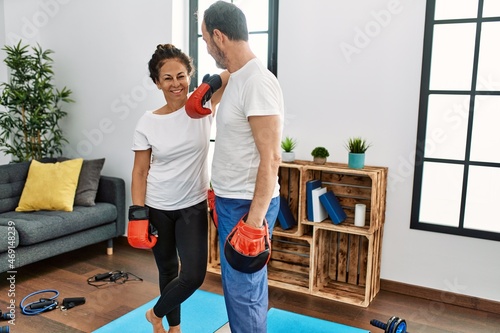 Middle age hispanic couple smiling happy training boxing at home.