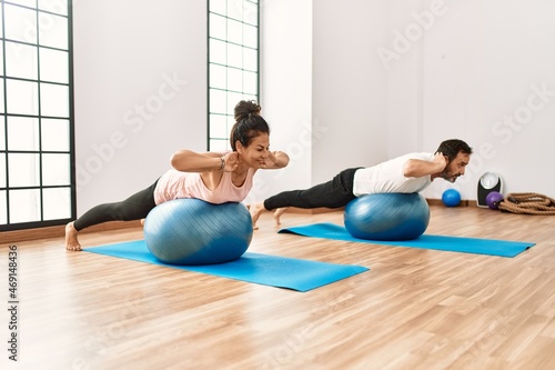 Mature hispanic couple doing excersice and stretching at yoga room. Two adult people doing pilates and flexibility workout