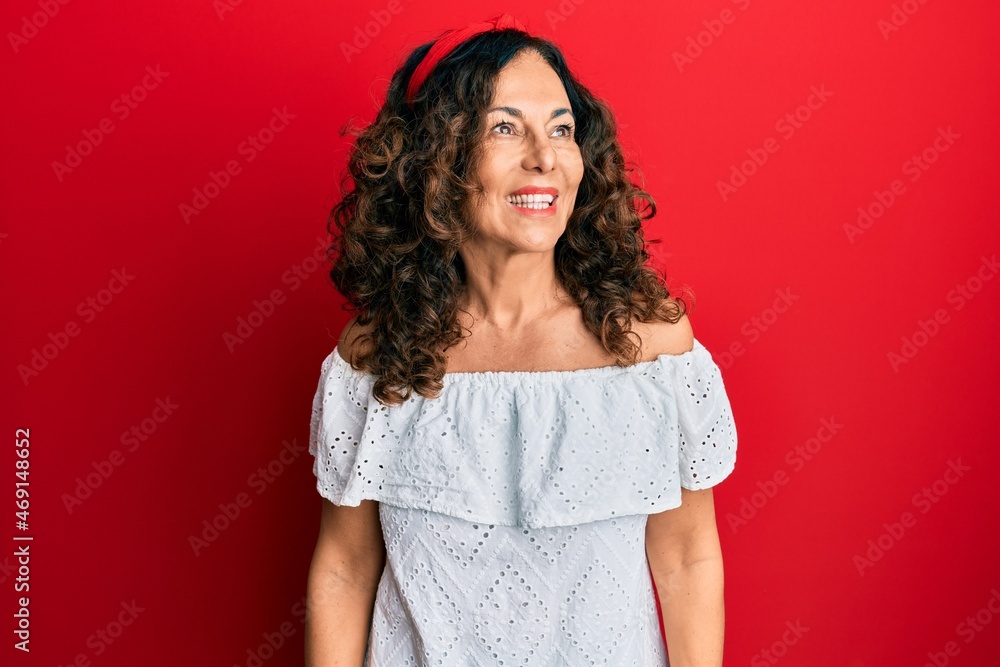 Middle age hispanic woman wearing casual clothes looking away to side with smile on face, natural expression. laughing confident. Middle age hispanic woman wearing casual clothes looking away to side with smile on face, natural expression. laughing confident.