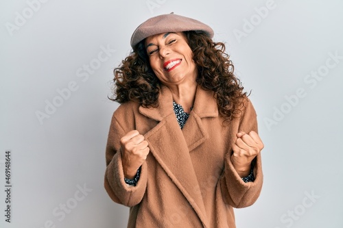 Middle age hispanic woman wearing french look with beret excited for success with arms raised and eyes closed celebrating victory smiling. winner concept.