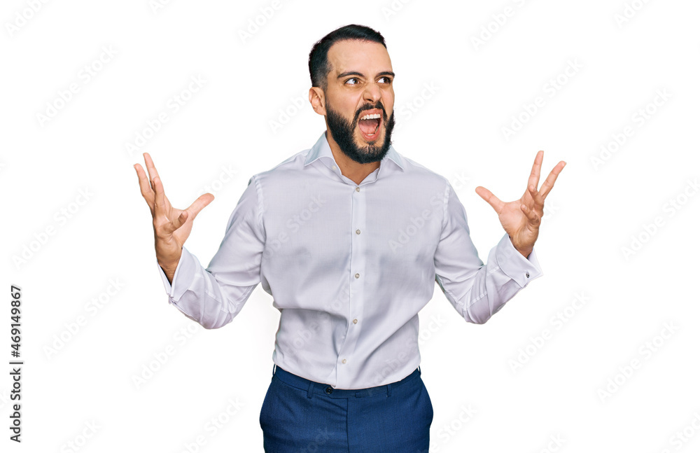 Young man with beard wearing business shirt crazy and mad shouting and yelling with aggressive expression and arms raised. frustration concept. Young man with beard wearing business shirt crazy and mad shouting and yelling with aggressive expression and arms raised. frustration concept.
