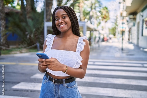 Young african american girl smiling happy using smartphone at the city.
