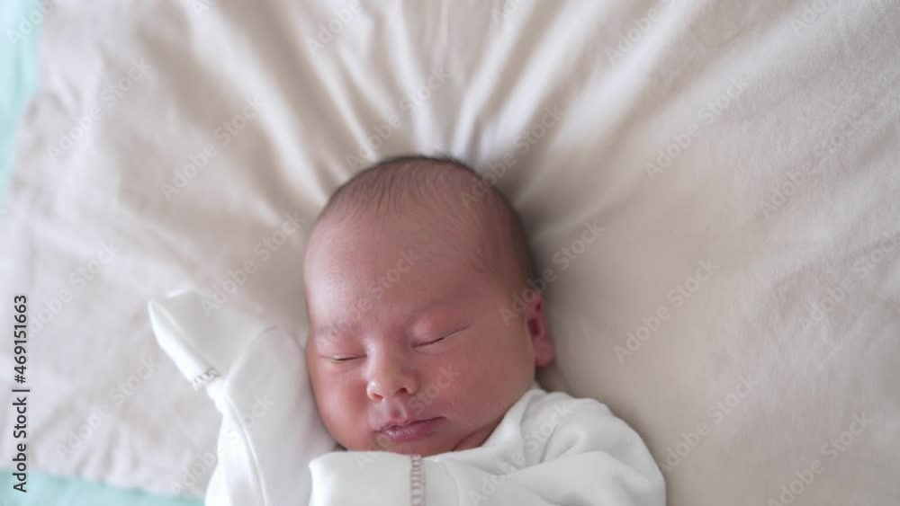 Infant baby. Portrait of a newborn baby in white clothes lying the bed. Cute baby boy waking up and blinking his eyes. Close-up. Infant baby. Portrait of a newborn baby in white clothes lying the bed. Cute baby boy waking up and blinking his eyes. Close-up.