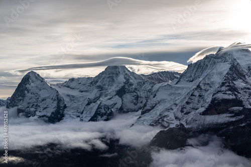 View of the famous peaks Jungfrau  M  nch and Eiger from the Schilthorn in the Swiss Alps Switzerland over the Lauterbrunnen Valley at sunrise with dramatic clouds and fresh snow.