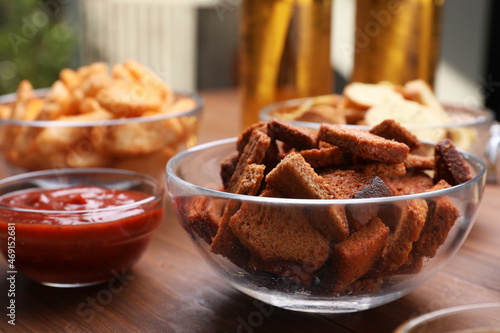 Crispy rusks and dip sauce on wooden table, closeup