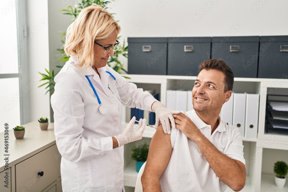 Middle age man and woman doctor and patient vaccinating at clinic