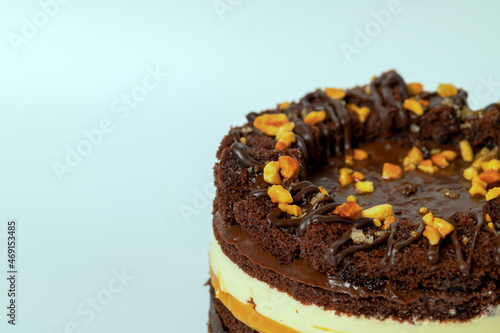 Close up part of chocolate cake with caramel and peanuts on green background.