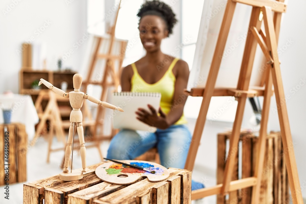 Obraz premium Young african american artist woman drawing manikin on notebook at art studio.