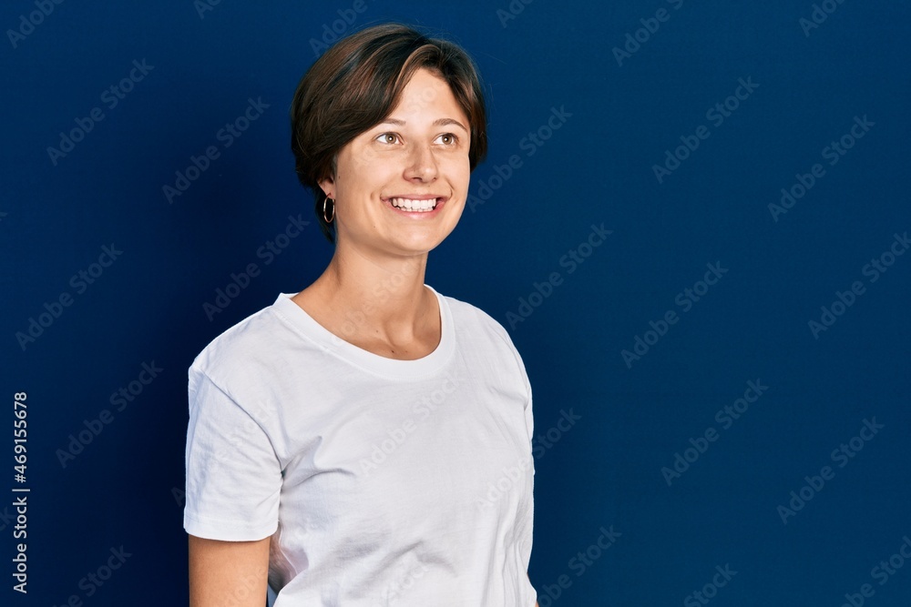 Young caucasian woman with short hair wearing casual white t shirt smiling happy standing over isolated background Young caucasian woman with short hair wearing casual white t shirt smiling happy standing over isolated background