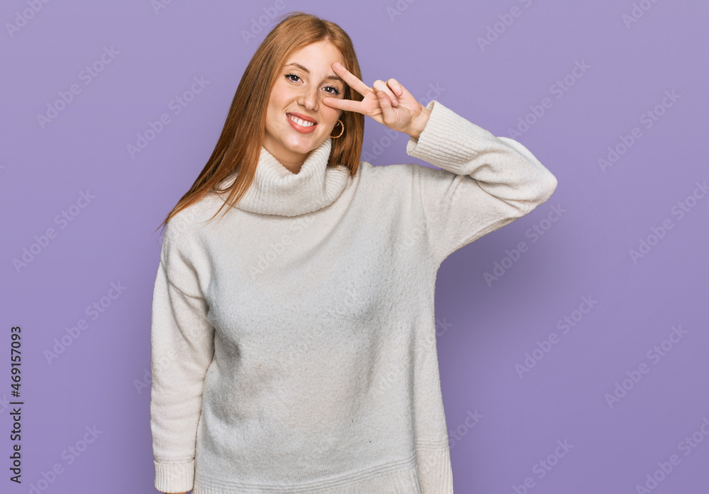 Young irish woman wearing casual winter sweater doing peace symbol with fingers over face, smiling cheerful showing victory Young irish woman wearing casual winter sweater doing peace symbol with fingers over face, smiling cheerful showing victory