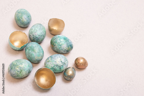 Stylishly colored Easter eggs. Inside of the golden shell, chicken and quail eggs are decorated with blue and turquoise paint, with non-uniform surface. Interesting idea for Easter decor. Copy space