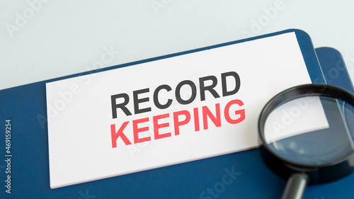 text record keeping on white paper card, black ahd red letters. lens on blue background. business concept. education concept photo