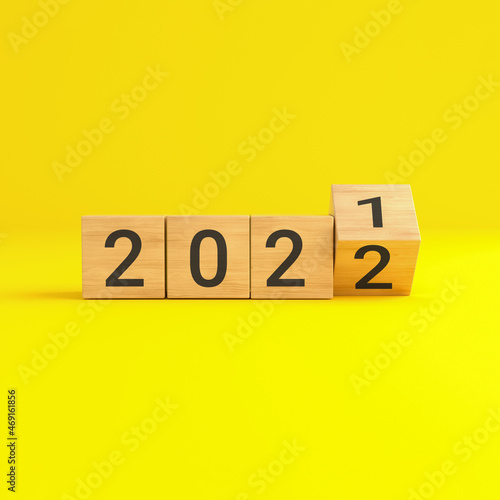 Flip over wooden cube block with new year 2022 on yellow background.