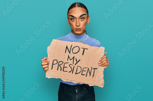 Obraz na plátně Hispanic transgender man wearing make up and long hair holding not my president