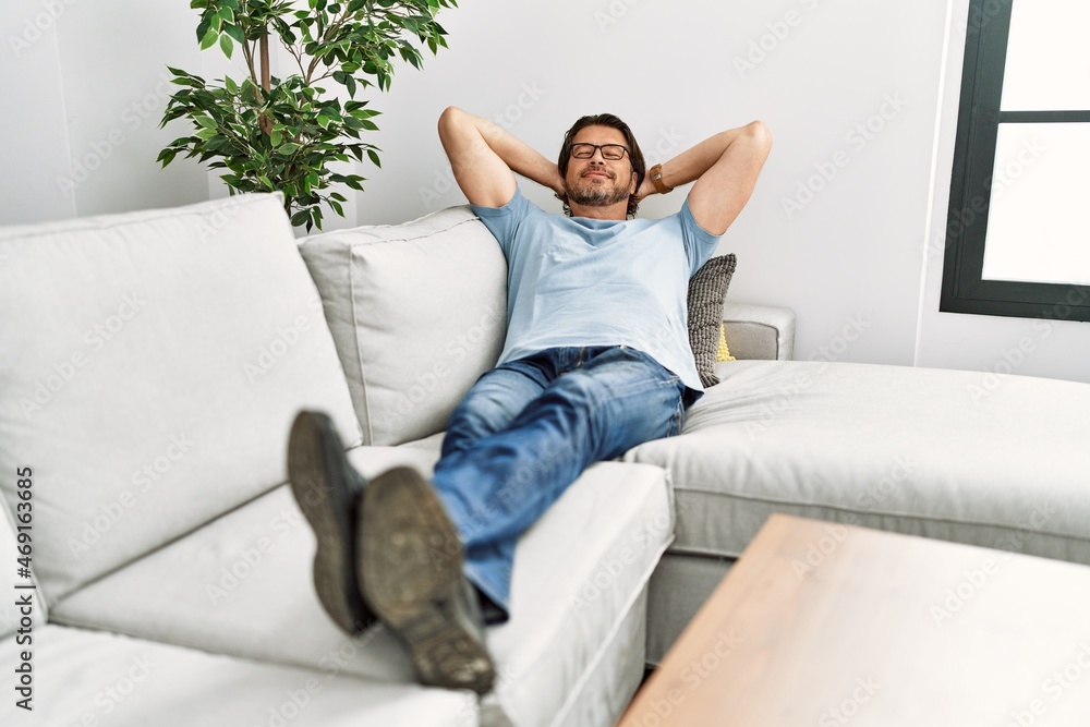 Middle age caucasian man relaxed with hands on head lying on sofa at home Middle age caucasian man relaxed with hands on head lying on sofa at home