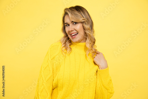 Portrait of cheerful playful young woman with blond hair showing tongue on yellow background. cute caucasian lady look at camera charmingly, dating concept, flirting © Татьяна Волкова