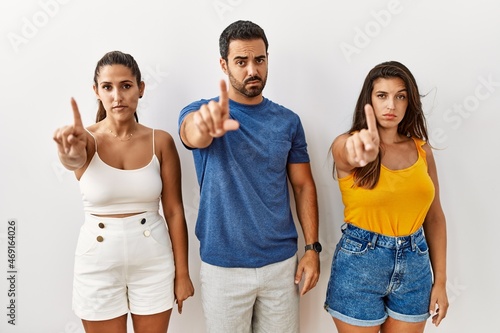 Group of young hispanic people standing over isolated background pointing with finger up and angry expression  showing no gesture