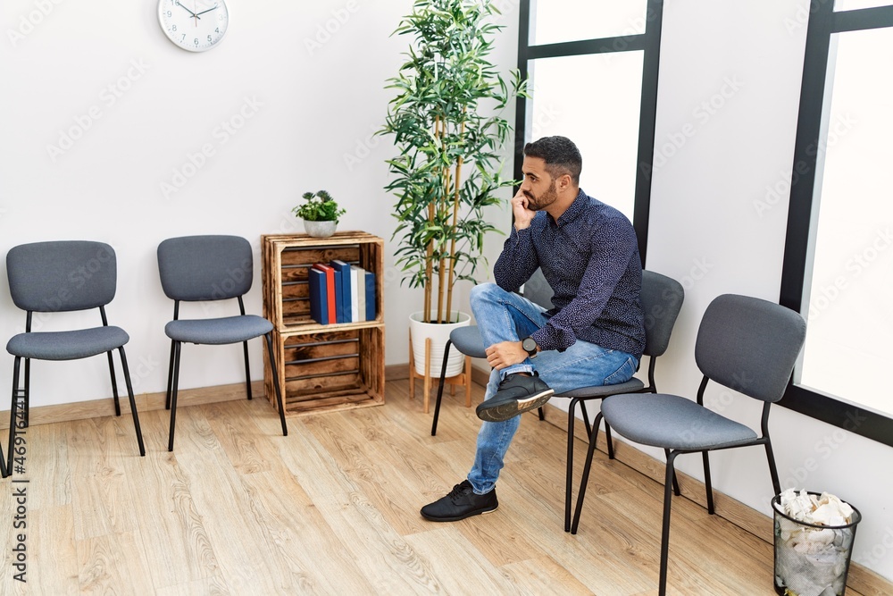 Young hispanic man desperate sitting on chair at waiting room Young hispanic man desperate sitting on chair at waiting room