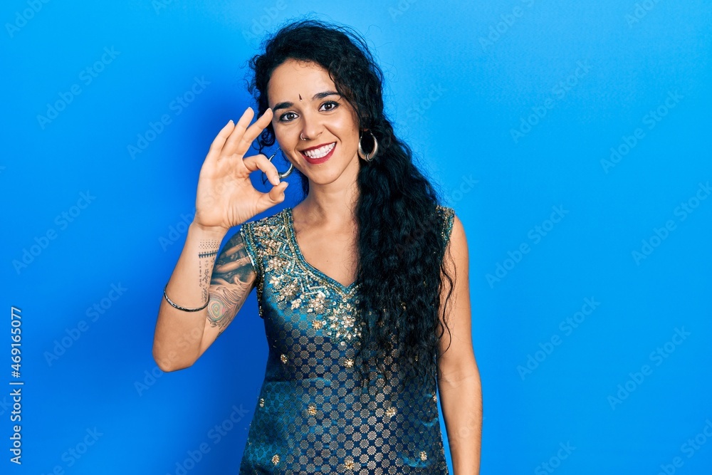 Young woman wearing bindi and traditional kurta dress smiling positive doing ok sign with hand and fingers. successful expression. Young woman wearing bindi and traditional kurta dress smiling positive doing ok sign with hand and fingers. successful expression.