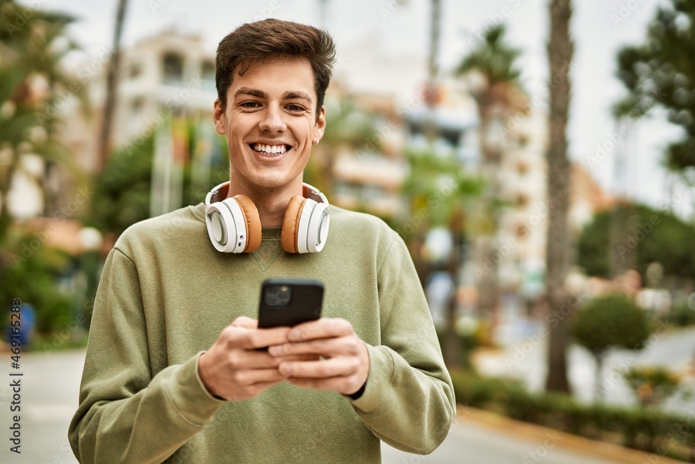 Young hispanic man smiling happy using smartphone and headphones at the city. Young hispanic man smiling happy using smartphone and headphones at the city.