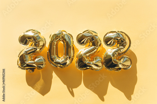 Balloons made of gold foil with the numbers 2022 on a gold background. Celebrating Christmas, New Years and holiday concept. Flat lay, top view.