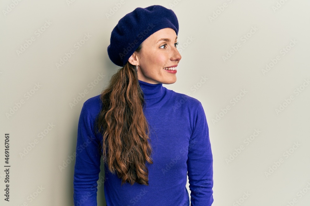 Young blonde woman wearing french look with beret looking to side, relax profile pose with natural face and confident smile. Young blonde woman wearing french look with beret looking to side, relax profile pose with natural face and confident smile.
