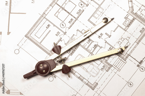 A large metal compass on the engineering plan of the house. Calculation and measurement of the house according to the construction drawing.