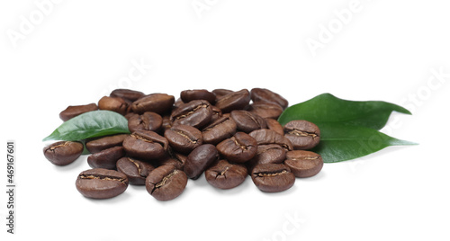 Pile of roasted coffee beans with fresh leaves on white background
