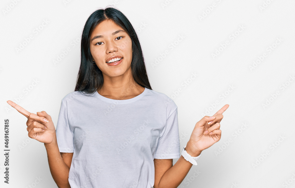 Beautiful young asian woman wearing casual white t shirt smiling confident pointing with fingers to different directions. copy space for advertisement Beautiful young asian woman wearing casual white t shirt smiling confident pointing with fingers to different directions. copy space for advertisement
