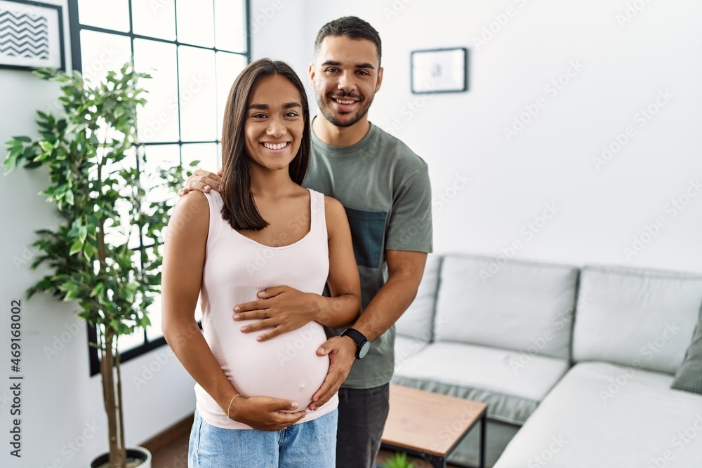 Young interracial couple expecting a baby, touching pregnant belly with a happy and cool smile on face. lucky person. Young interracial couple expecting a baby, touching pregnant belly with a happy and cool smile on face. lucky person.