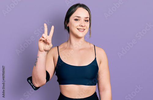 Young hispanic woman wearing sportswear showing and pointing up with fingers number two while smiling confident and happy.