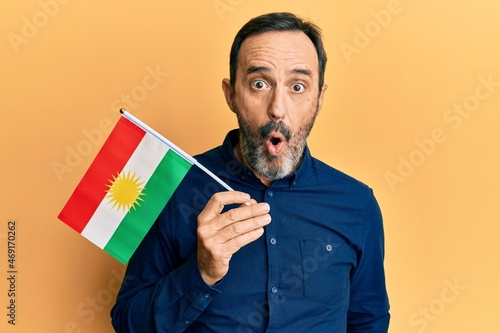 Middle age hispanic man holding pakistan flag scared and amazed with open mouth for surprise, disbelief face photo
