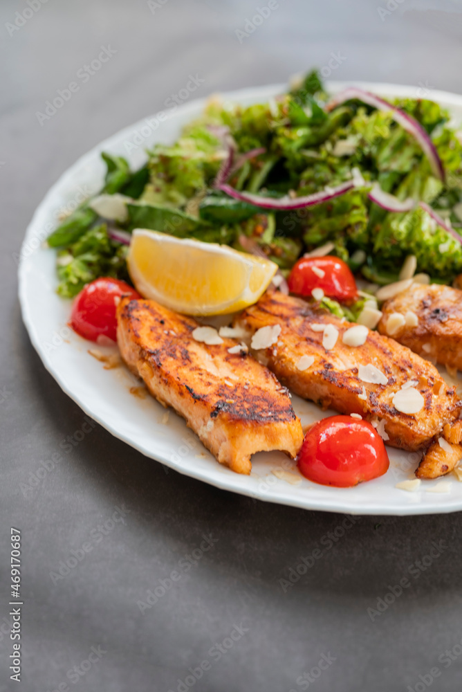salad dish with slices of baked fried salmon with vegetables and lettuce salad dish with slices of baked fried salmon with vegetables and lettuce