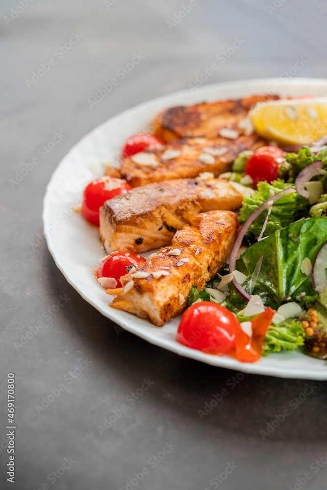 salad dish with slices of baked fried salmon with vegetables and lettuce salad dish with slices of baked fried salmon with vegetables and lettuce