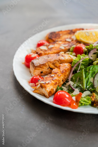 salad dish with slices of baked fried salmon with vegetables and lettuce