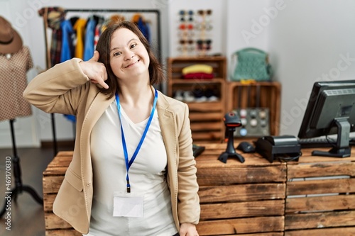 Εκτύπωση καμβά Young down syndrome woman working as manager at retail boutique smiling doing phone gesture with hand and fingers like talking on the telephone