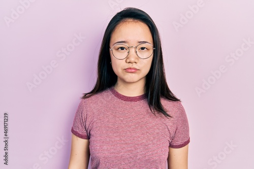 Young chinese girl wearing casual clothes and glasses depressed and worry for distress, crying angry and afraid. sad expression.