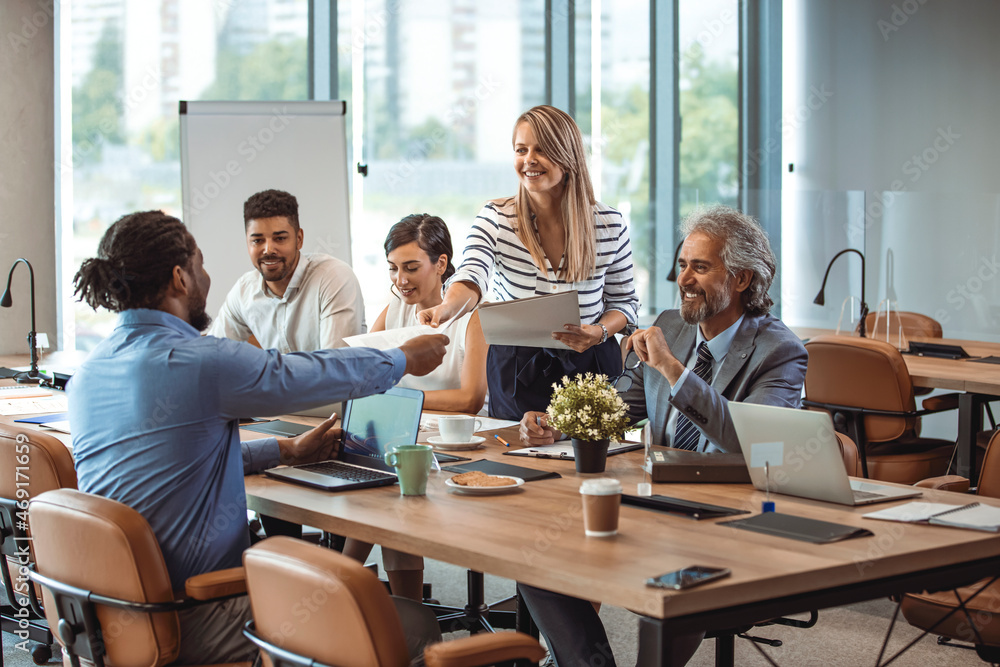 Obraz premium Multi-ethnic group of entrepreneurs discussing business. Finding solutions together. Multi-ethnic professionals are discussing while sitting at desk in office. Team of young architects working