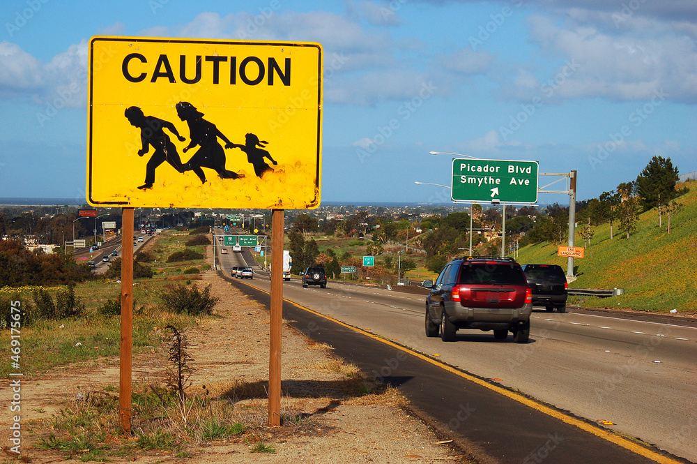 A sign on the highway near San Diego, California warns drivers to beware of  immigrants and migrants crossing the busy freeway Photos | Adobe Stock