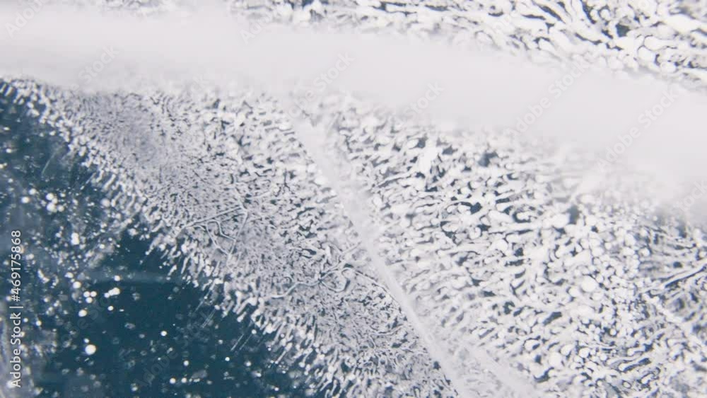 A plenty of tiny white bubbles inside turquoise thick clear ice. Frozen texture. A plenty of tiny white bubbles inside turquoise thick clear ice. Frozen texture.