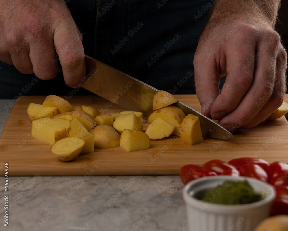 A man Cuts Vegetables on a Wooden Cutting Board. A man Cuts Vegetables on a Wooden Cutting Board.